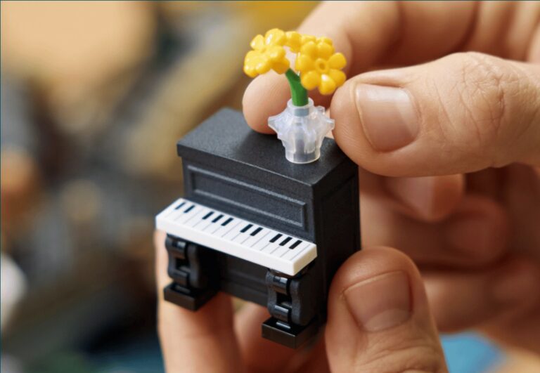 3D printed LEGO street piano with a flower bouquet on top, held between two fingers